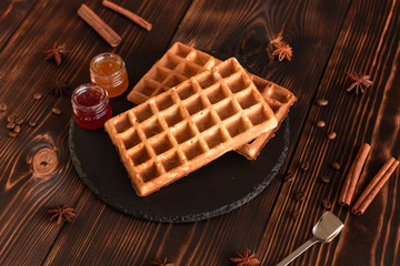 Tasty fresh Vienna wafers, jam and cup of coffee on a dark wooden background