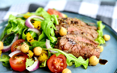 Steak Salad with Honey Soy Pan Sauce on blue dish..Beef salad with Arugula and chickpeas.