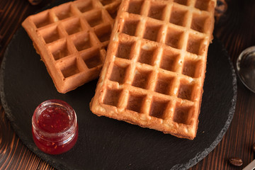 Tasty fresh Vienna wafers, jam and cup of coffee on a dark wooden background