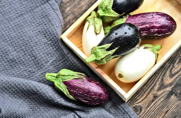 3 colorful mixed of Eggplant (Solanum melongena) or aubergine with water drop in wooden box on wooden background. © posinote