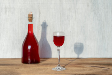 Bottle and glass of homemade raspberry liqueur