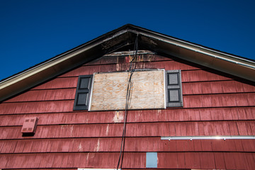 Window boarded up after house fire with roof and eves charred.