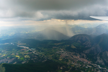Luftaufnahme aus einem Segelflugzeug mit Blick über eine Berglandschaft im Regen