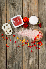 facial mask and moisturizer with roses on weathered wooden