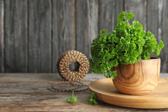 Bowl with fresh green parsley on wooden table. Space for text