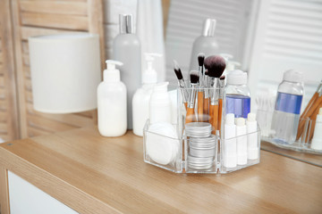 Organizer with cosmetic products on wooden table in bathroom