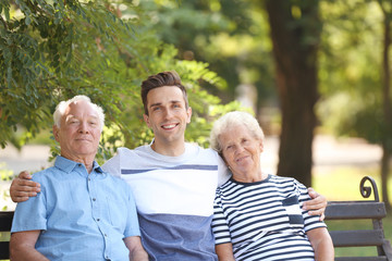 Man with elderly parents on bench in park