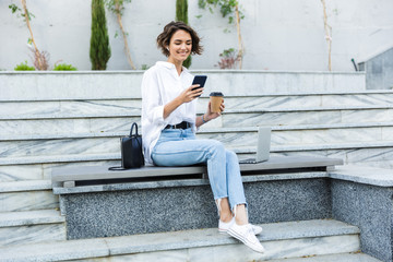 Beautiful young woman in earphones sitting outdoors