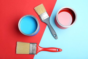 Flat lay composition with paint cans and brushes on color background