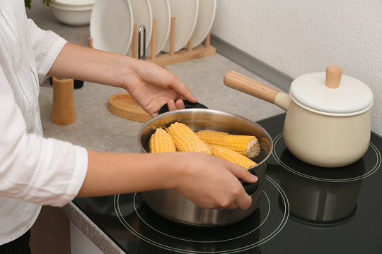 Woman preparing corn in stewpot on stove, closeup