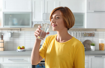 Woman drinking clean water from glass in kitchen