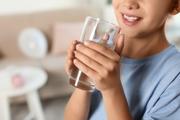 Little boy holding glass of fresh water at home, closeup