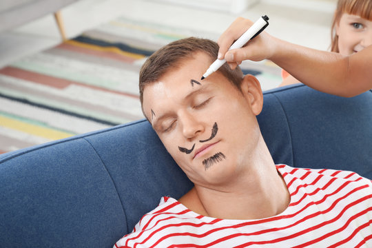 Child painting father's face while he sleeping on April Fool's Day