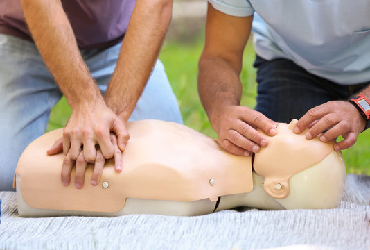People having first aid class with mannequin outdoors