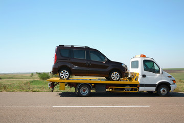 Fototapeta na wymiar Tow truck with broken car on country road