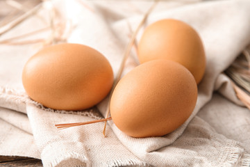 Raw brown chicken eggs on sackcloth, closeup view