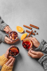 Women holding cups with hot mulled wine on table, top view