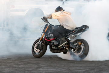biker burning tire and creating smoke on bike in motion