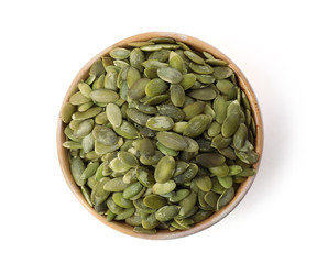 Shelled raw pumpkin seeds in bowl on white background, top view