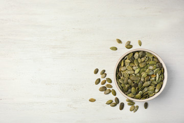 Shelled raw pumpkin seeds on wooden background, top view. Space for text