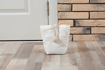 Fototapeta na wymiar Stuffed bag near white door at home
