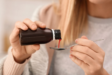 Woman taking cough syrup, closeup view