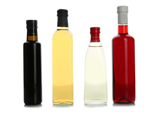 Glass bottles with different kinds of vinegar on white background