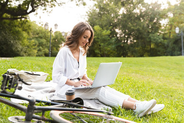 Lovely young woman bicyclist spending time at the park