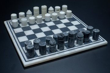 A game of chess with a modern black and white stone set of chess pieces