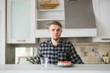 People, breakfast and drinks concept - handsome bearded young man is drinking coffee in kitchen