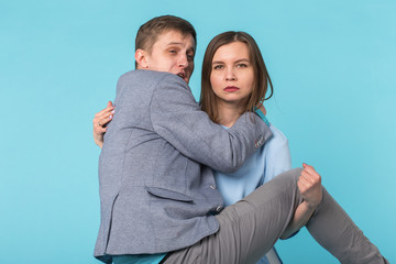 Family problems, responsibility, feminism and relationship concept - Woman carrying man in her arms on blue background