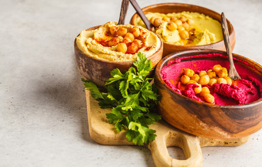 Different hummus bowls. Chickpea hummus, avocado hummus and beetroot hummus, copy space.