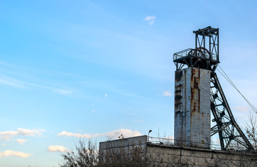Coal mine with wheels. Colliery against the blue sky with clouds