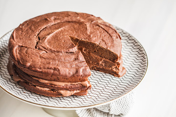 Vegan chocolate cake on a white dish for cake, copy space, light background.