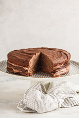 Vegan chocolate cake on a white dish for cake, copy space, light background.