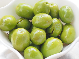Olivas verdes con hueso servidas en bol blanco de cerámica.