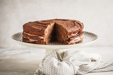 Vegan chocolate cake on a white dish for cake, copy space, light background.