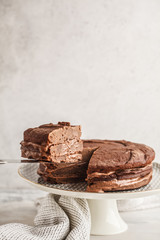 Vegan chocolate cake on a white dish for cake, copy space, light background.