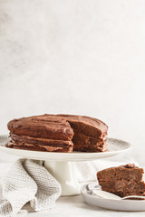 Vegan chocolate cake on a white dish for cake, copy space, light background.