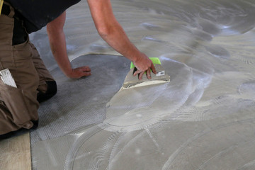 Work on laying flooring. Worker installing new vinyl tile floor.