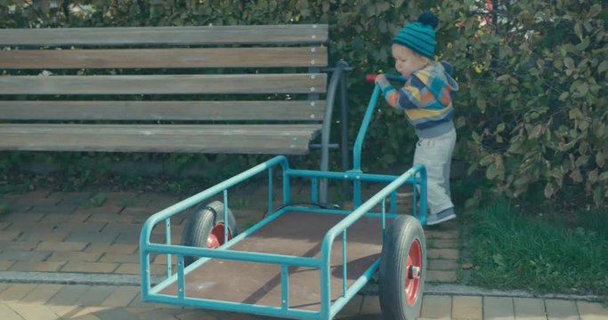 Little toddler boy playing with trailer