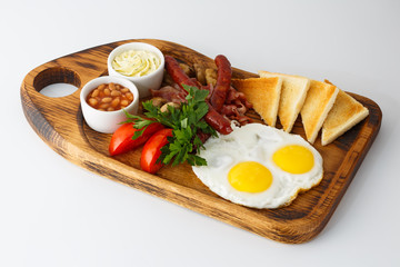 breakfast of fried eggs and grilled sausages on a wooden board isolated on white background