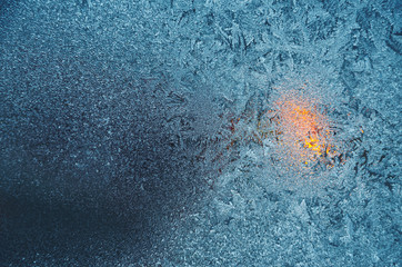 Icy frosty pattern on a window with candle fire behind.Christmas background.Rime...