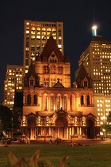 Nighttime photo of Trinity Church Boston, MA in Copley Square with buildings in the background