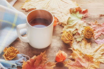 Top view orange coffee Cup framed by autumn colored maple leaves on a brown wooden Board background. Art. Soft focus