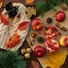 Apples, pomegranate, cinnamon, cones, walnuts, fallen leaves on a wooden background. Autumn composition.