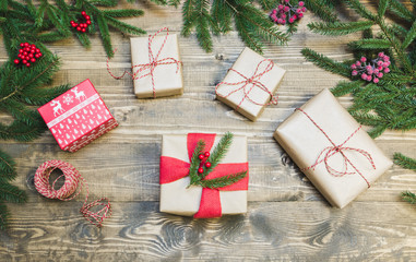 Christmas holiday background - gifts, holly berries and decoration on wooden board. Holiday card. Top view.