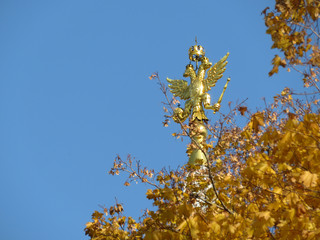 Coat of arms of Russia on blue sky, view through autumn trees. Golden Imperial eagle, Russian state...
