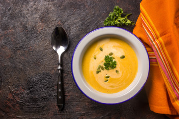 Seasonal autumn food - Spicy pumpkin soup with cream and pumpkin seeds.