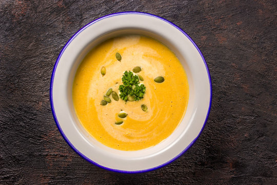 Seasonal autumn food - Spicy pumpkin soup with cream and pumpkin seeds.